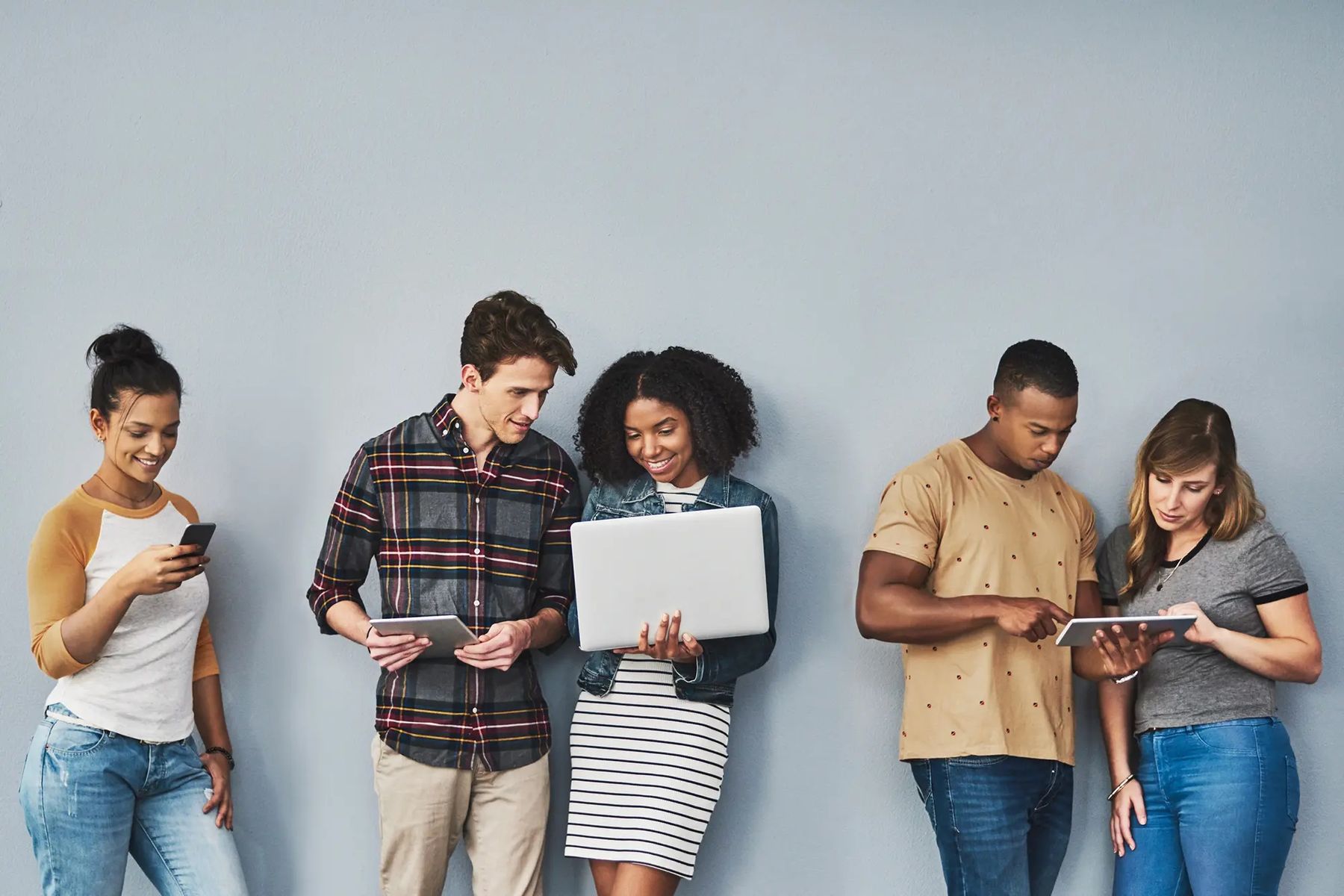 A group of young people with phones, tablets and a laptop